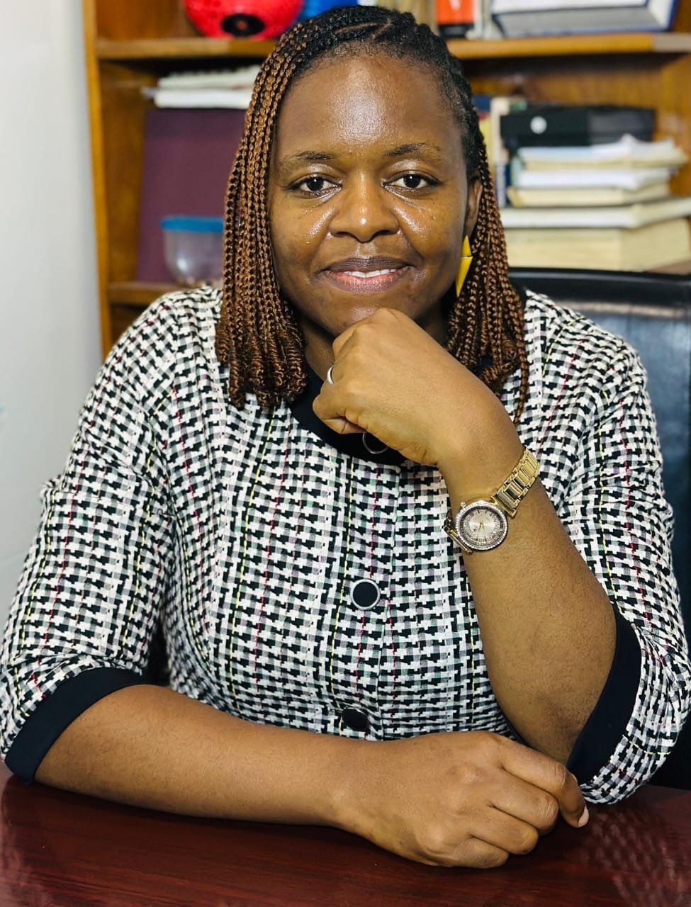 Mrs. Victorine Nasam, Academic Dean of GHITS University, professional portrait in white and black attire at desk